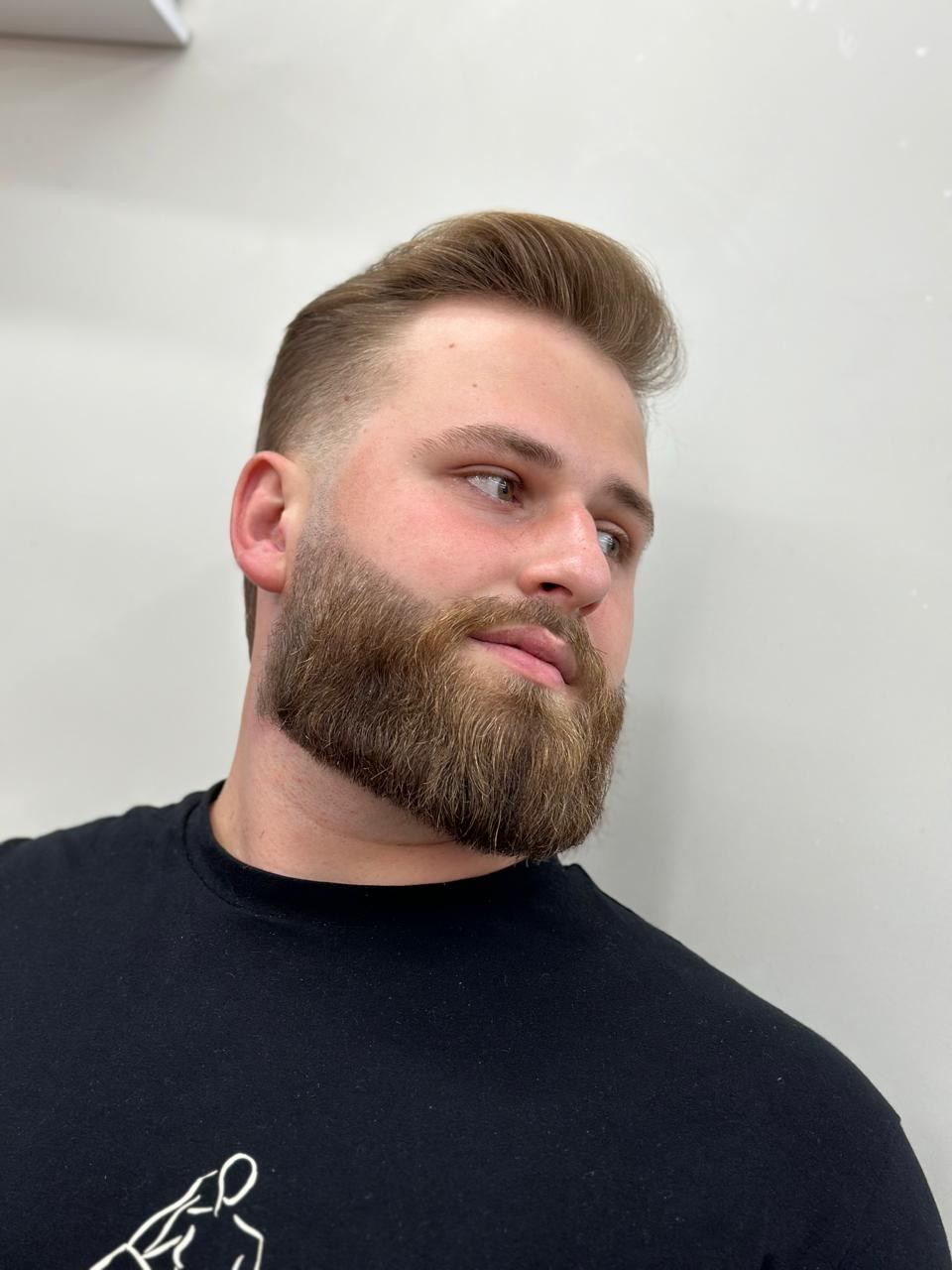 Cliente com barba cheia modelada e degradê nas laterais
