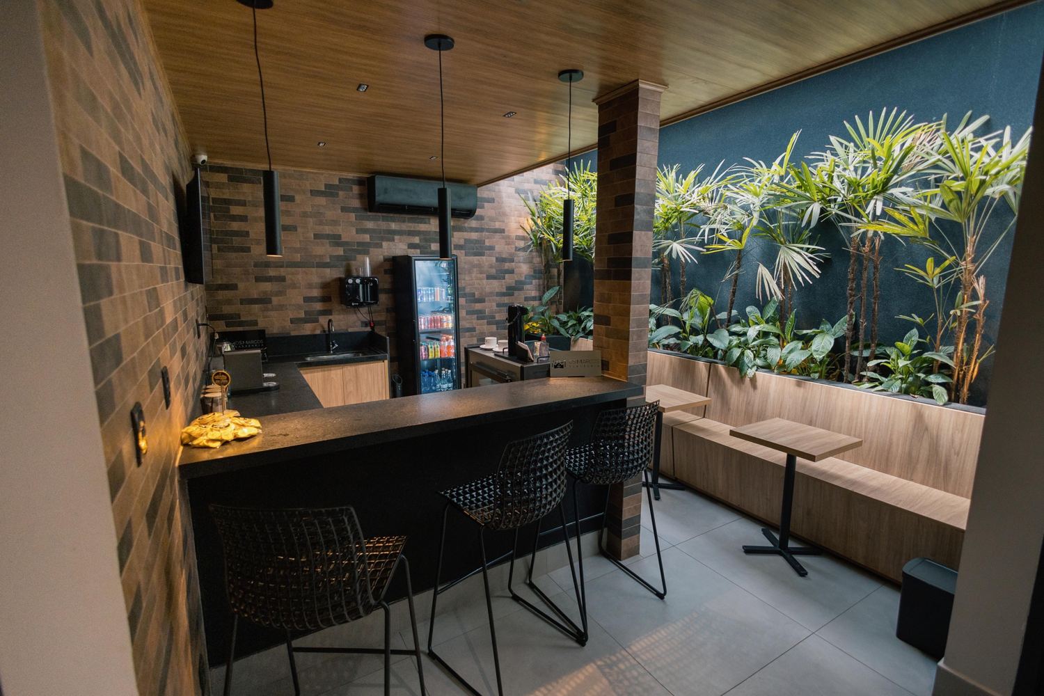Lounge com bar, bancos altos e jardim vertical